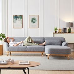 a man laying on top of a couch in a living room next to a table