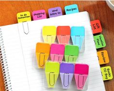 several different colored clips on top of a notepad with words written in each one