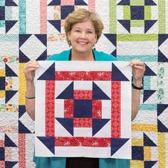 a woman holding up a piece of quilt