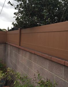 a brown fence next to a brick wall and potted plants on the side of it