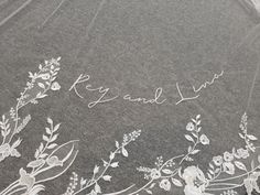 an embroidered veil with white flowers and leaves on it that says, ryan & liv