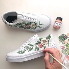 someone is painting flowers on their white shoes