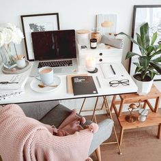 a white desk topped with a laptop computer next to a potted plant