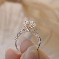 a person holding a diamond ring in their hand with the engagement ring on it's finger