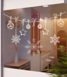 the window is decorated with snowflakes and baubles on a line,