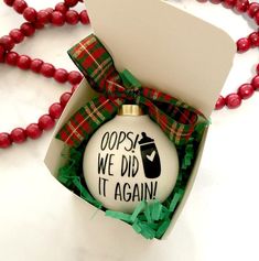 a christmas ornament in a gift box on a bead necklace that says, copse we did it again