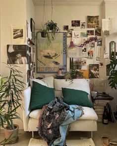 a living room filled with lots of plants and pictures hanging on the wall above it