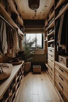 a walk in closet with lots of wooden drawers and clothes hanging on the shelves next to it