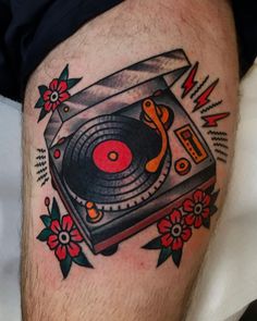 a man's thigh with an old school record player and flowers on the side