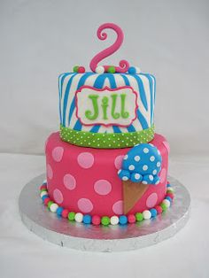 a pink and blue birthday cake with an ice cream cone on the top, polka dot