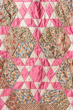 a pink and white quilt with many different designs on it's sides, including triangles