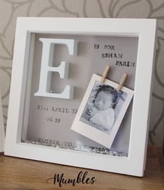 a photo frame with clothes pins attached to it and the letter e hanging on a clothes line