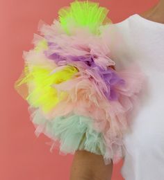 a woman wearing a white shirt and colorful tulle