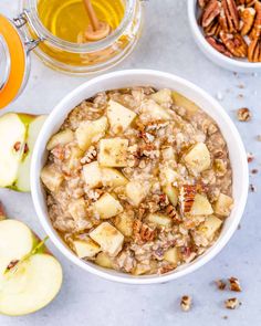 oatmeal with apples, pecans and honey in a white bowl on a table