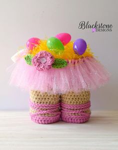 a crocheted basket with easter eggs and flowers on the top, sitting on a table