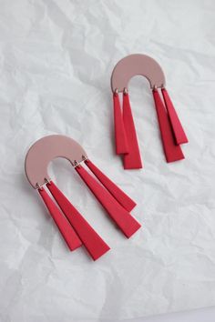 two pairs of pink and red earrings on white paper