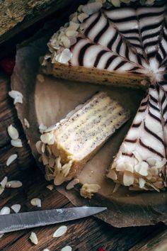 there is a cake with white frosting and nuts on the table next to a knife