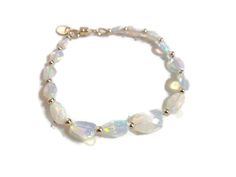 This opal bracelet created by Jewelry by CARMAL is made of nugget natural Ethiopian opal gemstones, 14k gold: beads, and magnetic clasp closure. This bracelet measures 7 1/2 inches in length and is finished with at 14k gold oval charm.  The pictures do not do this bracelet justice! This bracelet would go great with these earrings: https://www.etsy.com/listing/1530862840/ethiopian-opal-earrings-october?click_key=ff8af590c11569fc9ae2a12061e1d30023f83387%3A1530862840&click_sum=89e7b0ab&ga_search_qu Oval Opal Bracelets As Gift, Oval Opal Bracelets For Gifts, Opal Gemstone Bracelet Jewelry, Elegant Ethiopian Opal Gemstone Beads Jewelry, Elegant Moonstone Gemstone Beaded Bracelets, Elegant White Beaded Bracelets With Gemstones, Elegant Iridescent Round Bead Bracelets, Elegant White Gemstone Beaded Bracelets, Elegant White Beaded Gemstone Bracelets