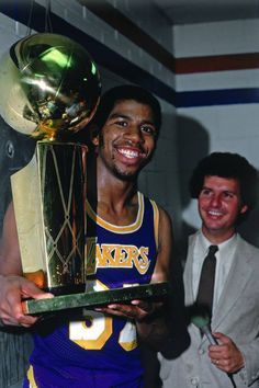 a man holding up a trophy next to another man