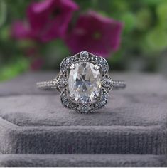 a close up of a ring on top of a box with flowers in the background