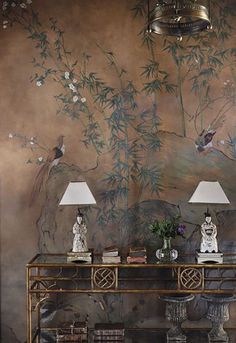 two lamps are sitting on a table in front of a wall with birds and flowers