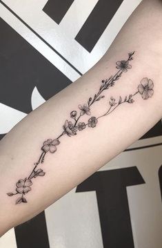 a woman's arm with flowers on it and the word love written in black ink