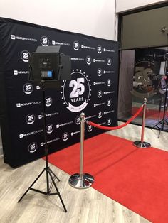 a red carpet and black backdrop in front of a stage with two microphones on it