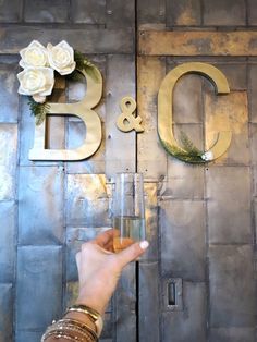 a person holding a wine glass in front of a metal sign that says b & g