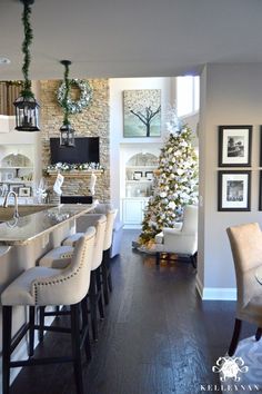 a living room filled with furniture and a christmas tree in front of a bar area