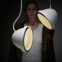 a woman is standing in front of two lamps that look like they are suspended from the ceiling