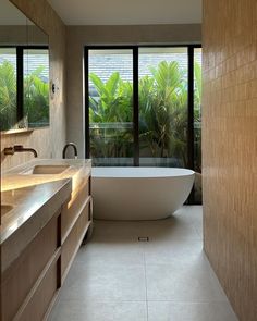 a bathroom with a tub, sink and large windows