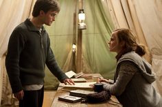 a man standing next to a woman in front of a table with books on it