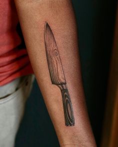 a person with a knife tattoo on their arm