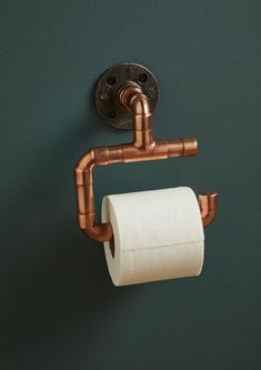 a toilet paper roll is hanging on the wall next to a copper faucet