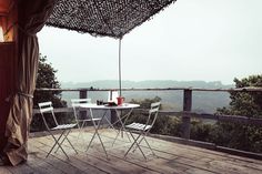 two chairs and a table on a deck overlooking the mountains with an umbrella over them