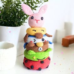 a stack of crocheted toys sitting on top of a table next to a potted plant