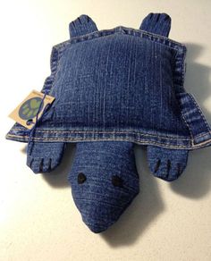 a blue stuffed animal laying on top of a denim pillow that has been made to look like a turtle