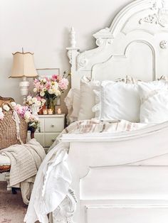 a bedroom with white furniture and flowers in vases