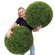 a woman holding two large bushes in her hands