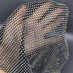 a woman's hand holding an umbrella covered in lots of silver and black sequins