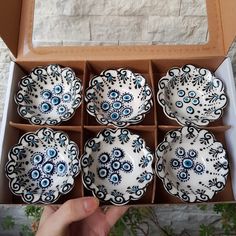 six blue and white dishes in a box with one being held up to the camera