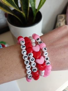 a woman's arm with two bracelets that have hearts and words on them