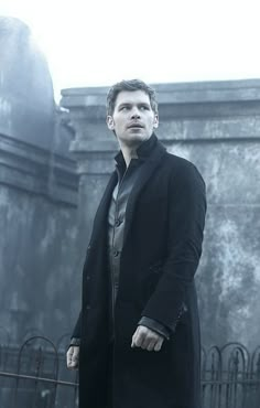 a man in a black coat is standing outside