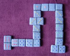 two pieces of knitted fabric sitting on top of a purple blanket