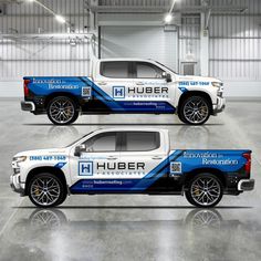 two white trucks with blue stripes parked in a garage