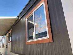 the side of a house with a large window and siding on it's sides