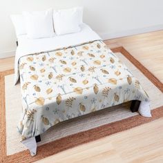 a bed with a floral comforter on top of it next to a wooden floor