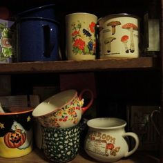 there are many mugs on the shelf together