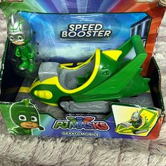 a green and yellow toy car in a box on a carpeted surface with other toys