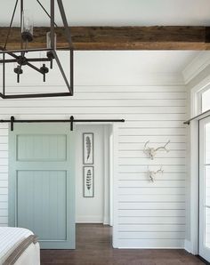 a bedroom with white walls and wood floors has a light fixture hanging from the ceiling